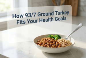 A white bowl on a marble counter filled with cooked 93/7 ground turkey, brown rice, and broccoli, beneath a transparent pane that says "How 93/7 Ground Turkey Fits Your Health Goals.