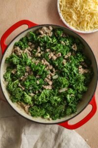 Cooked ground turkey mixed with sautéed kale and onions in a red pan, illustrating how added ingredients affect the final calorie count.