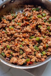 Cooked seasoned ground turkey in a pan with herbs