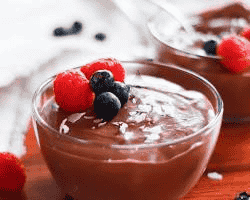 A slice of low-carb cheesecake topped with fresh berries alongside a bowl of dark chocolate mousse.